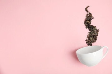 Dry tea brew and cup on pink background, flat lay. Space for text
