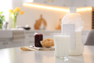 Gallon bottle of milk, glass and breakfast cereal on white table in kitchen. Space for text