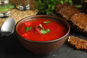 Stylish brown clay bowl with Ukrainian borsch on black table