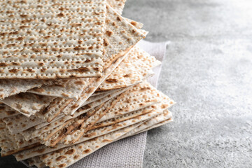 Stack of traditional matzos on grey table, closeup. Space for text