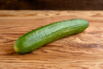 green cucumber on the wooden surface of the table