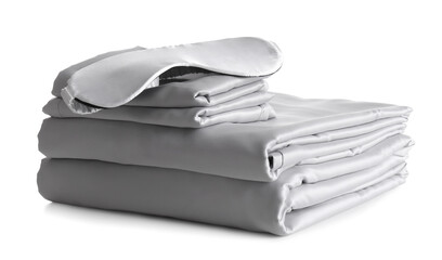 Stack of clean silky bed linen and sleeping mask isolated on white