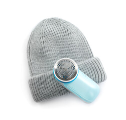 Modern fabric shaver and woolen hat on white background, top view