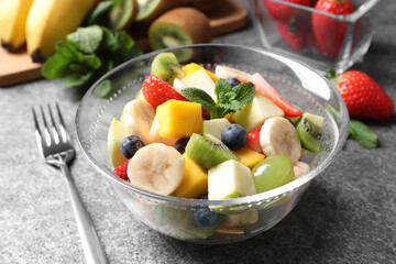 Fototapeta na wymiar Delicious fresh fruit salad in bowl on grey table
