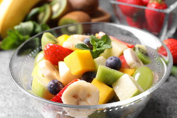 Delicious fresh fruit salad in bowl on table, closeup