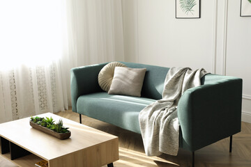 Soft green sofa and wooden table in living room. Interior design