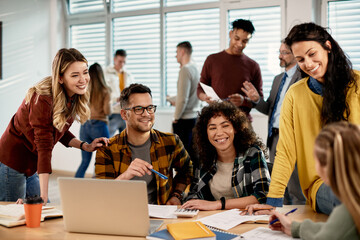 Group of happy college friends talking while studying in the classroom.
