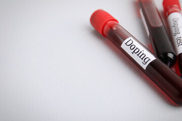 Closeup view of test tubes with blood samples on light grey background, space for text. Doping...
