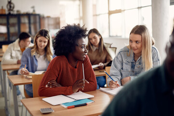 Female college students talking during a class in the classroom. - obrazy, fototapety, plakaty