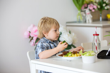 Little toddler child, blond boy, eating boiled vegetables, broccoli, potatoes and carrots with fried chicken meat at home