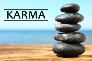 Karma concept. Stack of stones on wooden surface against seascape
