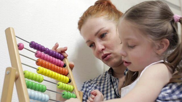 The child sits with his mother, counts the accounts. . Children's wooden toy. Educational logic toys for children. Montessori games for child development.