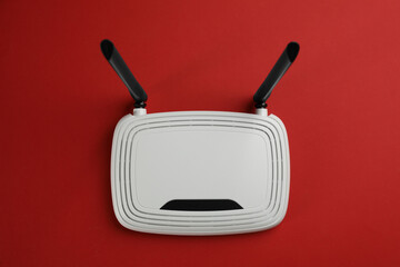 Modern Wi-Fi router on red background, top view