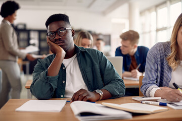Black male student feeling bored during class at the university.