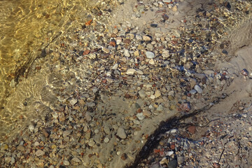Abstract view of the river with small stones, ripple, sand pattern, yellow colors, sunny day