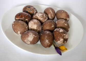 Easter eggs on a plate, European Easter with traditional decoration eggs, easter eggs decorated with natural fresh leaves and boiled in onions peels and blueberry berries