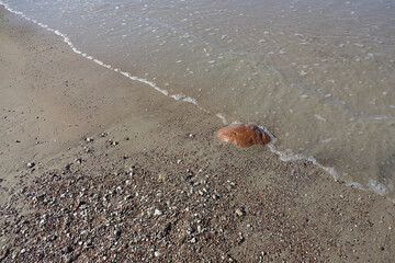 Stone in diagonal in betwwen of sand and sea water coming, sunny day, pebble and small stones