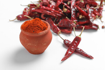 Red chilli powder with dried red chillies. in earthen bowl.