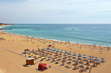 Portugal. Algarve. People are relaxing on a sandy town beach by the sea in summer holidays. Seaside rest conception, top view
