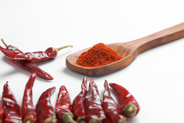 Chilli powder in wooden spoon with dry red chilly on white background.