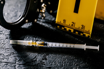 Heroin in a syringe on the dark cement floor. An addictive substance, a drug, an illegal thing, the...