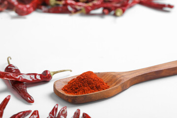 Chilli powder in wooden spoon with dry red chilly on white background.