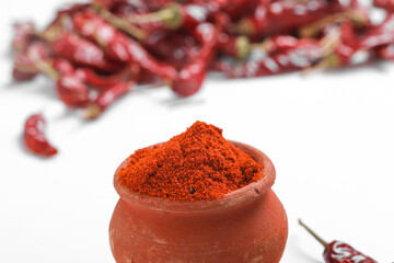 Red chilli powder with dried red chillies. in earthen bowl.