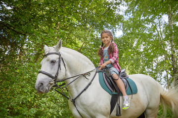 A teenage girl and a horse in nature among green trees