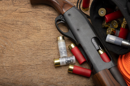 Pump action shotgun and bullet shells on wooden background , Clay pigeon shooting game