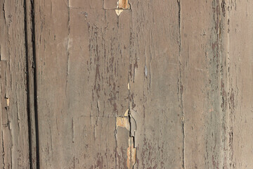 The surface of the wooden door with weathered, peeling paint. The texture of old wooden boards.