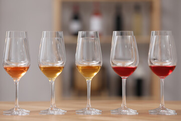 Different sorts of wine in glasses prepared for tasting on wooden table indoors