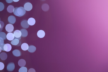 Blurred view of festive lights on purple background, space for text. Bokeh effect