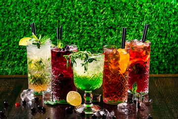 Selection of gin tonic with blackberries, with orange, with lime and mint leaves. In glasses on a...