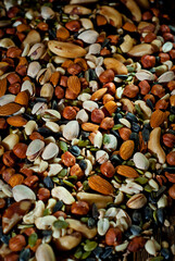 Many types of nuts close up. Textures of different nuts. Nuts are dumped in a pile. Contrasting dramatic light as an artistic effect.