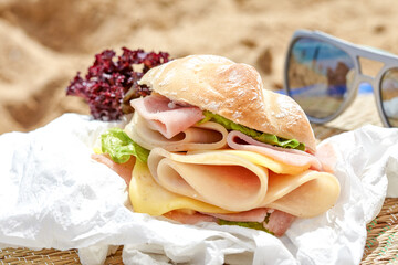 Sandwich with ham and cheese on a beach