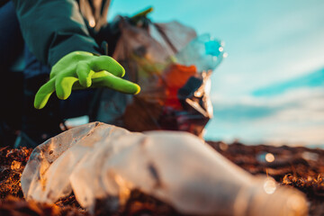 A worker in rubber gloes collects garbage on a sea beach. Hand close-up. The concept of Earth Day...
