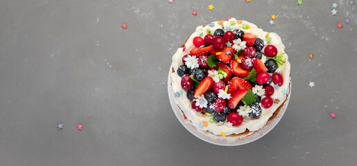 Delicious homemade cake with fresh berries and mascarpone cream on gray background.