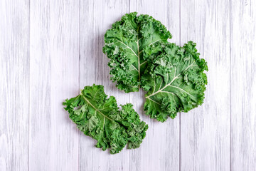 Kale leaves spread out on a wooden surface. Super food concept, healthy and vegetarian food. Selective focus.