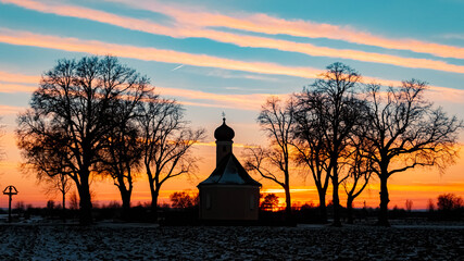 Fototapeta premium Beautiful sunset with a church silhouette and dramatic clouds near Wallersdorf, Bavaria, Germany