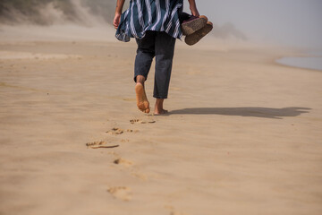 Midsection shot of woman walking along coastline