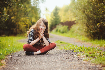 preteen 11 years old kid girl walking on summer countryside road, enjoying vacations outdoor