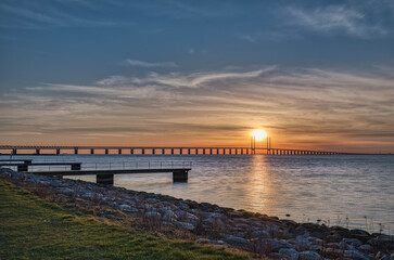 Fototapeta na wymiar Sunset on the Oresund Bridge (Oresundsbron) in the Baltic Sea. The road rail overpass connects Malmo to Copenhagen across the Oresund Strait and border commuters or frontier workers cross it daily