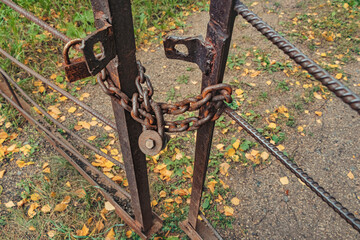 A rusty bolt lock on an old rusty chain on an iron gate. Left space concept or abandoned area.