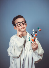 cool young boy is dressed as scientist with white lab coat and holding model of molecules in hand...