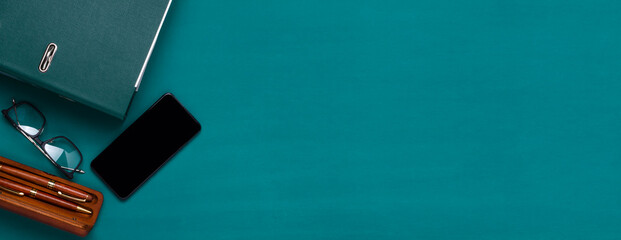 Top view of green holder for documents, glasses, pen on the dark green surface.Banner for ad