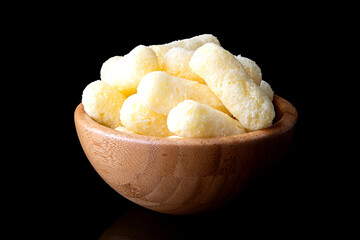 corn sticks in wooden bowl on black background