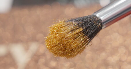 Brush gains glitter to be used in make-up. Macro view of working process, tools in beauty industry. Fashion glamour shiny glitter concept.