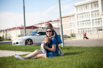 Fototapeta premium young mother with daughters are sitting on the grass
