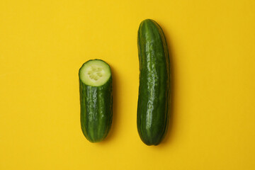 Ripe cucumber and half on yellow background
