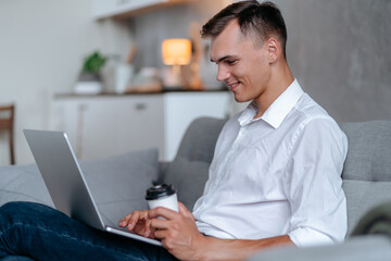 young man with a takeaway coffee reading his email .